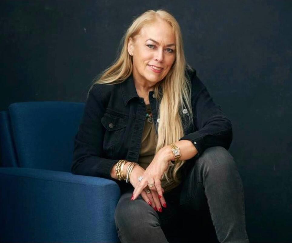 Barbara Amaya, blonde hair, dark blue jacket, smiling